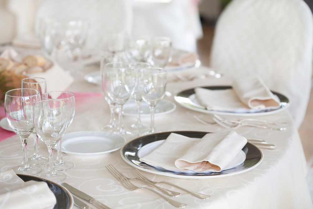 Experience the Party Plus Difference. The table on the front left showcases linens that have undergone our specialized commercial cleaning and pressing process. In contrast, the table on the back right features linens that were packaged in squares and not pressed, highlighting the clear distinction in quality.